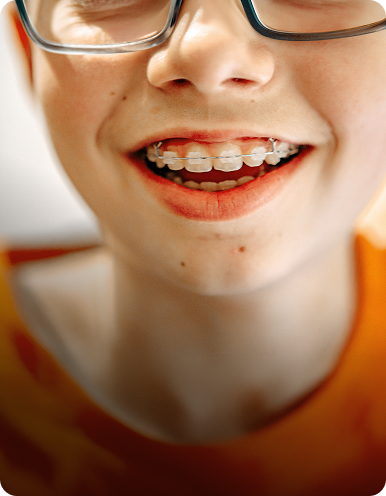Close-up portrait of a smiling child in glasses with braces visible.
